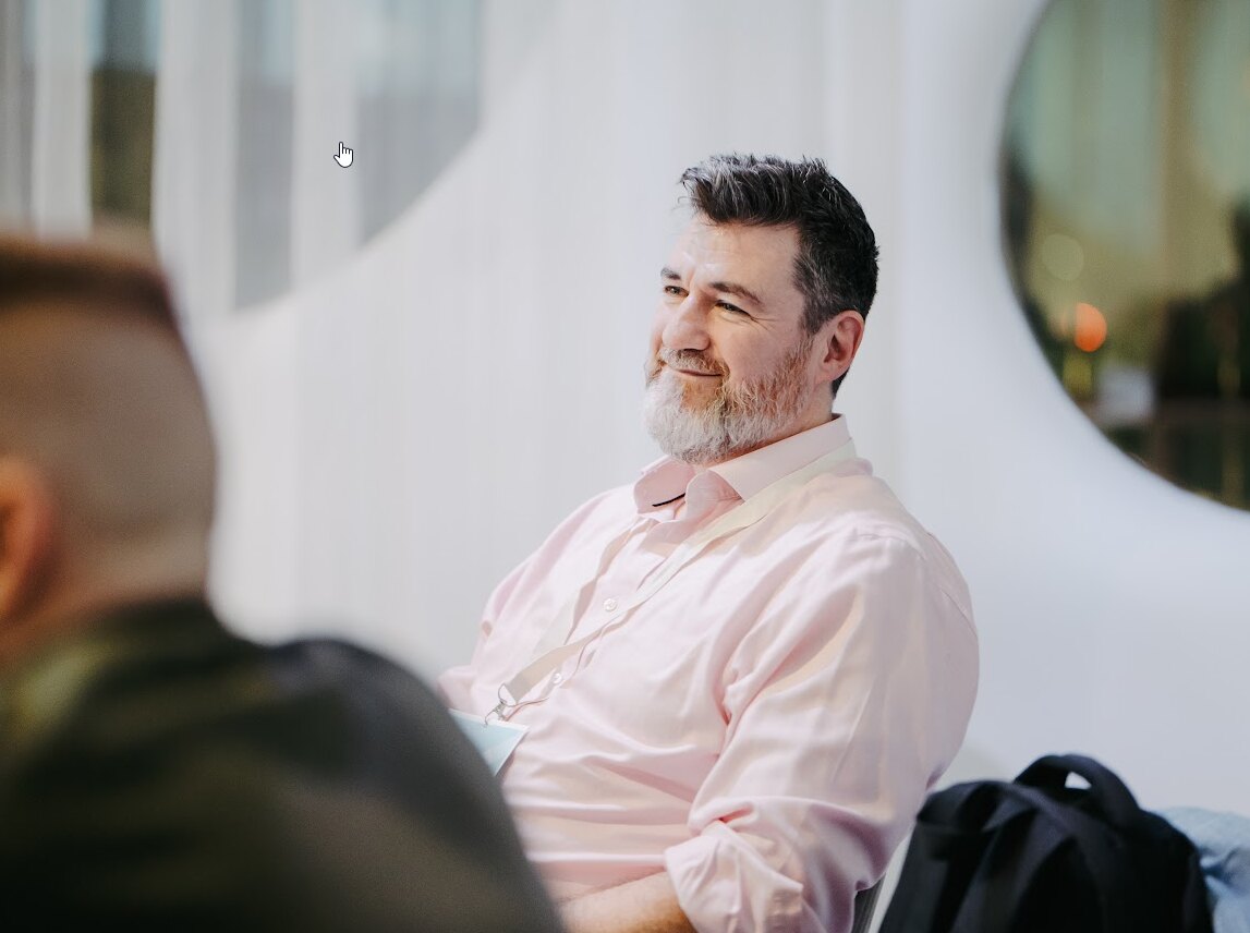 Tony Wood seated in a light shirt during a leadership conversation.